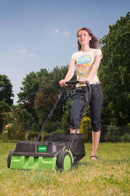 Une personne passe un aerateur-scarificateur electrique Une personne passe un aerateur-scarificateur electrique