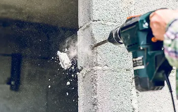 perforateur-burineur en action sur un mur de parpaing